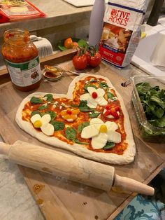 a heart shaped pizza sitting on top of a wooden cutting board