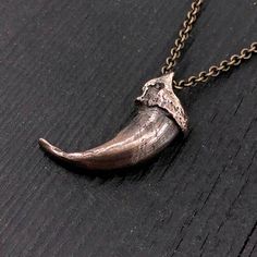 Discover the wild elegance of this unique wolf claw necklace, meticulously cast in solid jeweler's grade bronze from a real North American Gray Wolf claw. Measuring 1-1/4", this piece came from an exceptionally large specimen, making it a rare find. Every intricate detail of the original claw has been captured in this bronze recreation, slightly oxidized to enhance its deep, rich hue. Unlike typical designs, this necklace features a carefully bored hole through the knuckle, allowing the chain to Animal Accessories Jewelry, Brass Claw Jewelry As Gift, Viking Style Bronze Jewelry Gift, Hand Cast Claw Necklace As Gift, Medieval Brass Jewelry With Antique Finish, Bronze Hand Cast Round Pendant Necklace, Hand Cast Claw Necklace For Gift, Viking Style Hand-forged Jewelry Gift, Hand-forged Viking Style Jewelry Gift