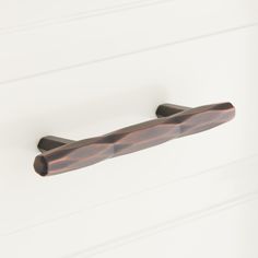 a close up of a door handle on a white wall with wood grained finish