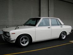 an old white car parked in front of a building