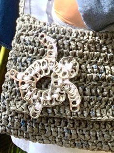 a crocheted purse with a butterfly brooch on the front and side, sitting on someone's lap