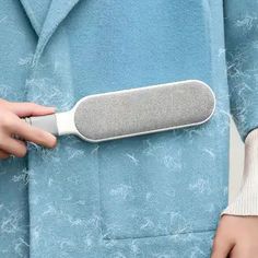 a person in a blue coat holding an electronic device that looks like a toothbrush