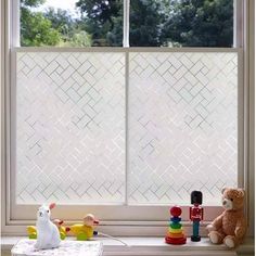 two teddy bears sitting on a window sill in front of a white tiled wall