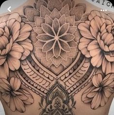 a woman's back with flowers and an intricate design on the top of it