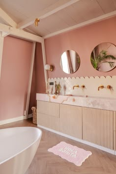 a bathroom with pink walls and two mirrors on the wall next to a bathtub