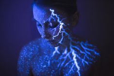 a woman with her body painted in blue and white lightning streaks on it's face