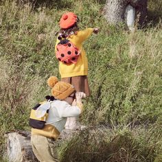 two children are playing in the grass with stuffed animals on their shoulders and one child is pointing