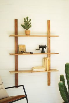 a wooden shelf sitting next to a cactus