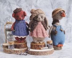 three knitted mice sitting on top of wooden stumps next to an empty bottle