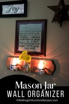 mason jar wall organizer hanging on the wall with candles and flowers in front of it