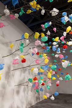 an art installation with colorful paper flowers hanging from it's branches and on the wall