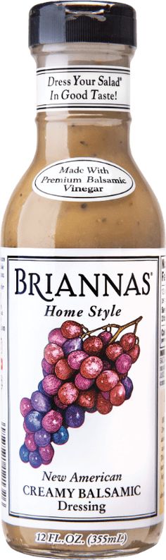 a jar of brown mustard with red and purple grapes on the side, in front of a white background