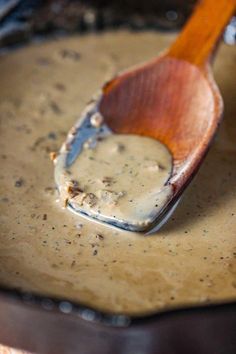 a wooden spoon with some food in it on a pan filled with gravy