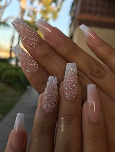 someone is holding their nails with some glitter on them, and there are two fingers in the foreground