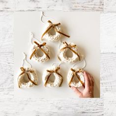 hand holding small white crocheted ornaments with brown bows