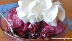 a dessert with whipped cream and cranberries in a glass bowl on a wooden table