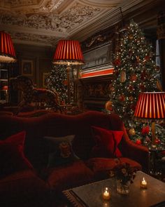 a living room filled with red couches next to a christmas tree and lit candles