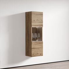 a wooden cabinet with wine glasses in it on the wall next to a white wall