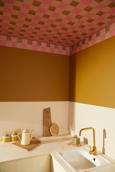 a sink and counter in a room with orange, pink, and yellow walls on the ceiling