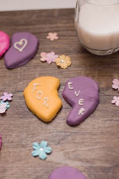 decorated cookies with the word love spelled on them next to a glass of milk and flowers