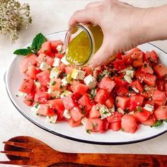 watermelon salad with feta cheese and mint oil being drizzled on top