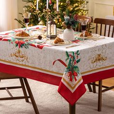 a dining room table with a christmas tree in the background and holiday decorations on it