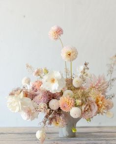 a vase filled with lots of flowers on top of a wooden table