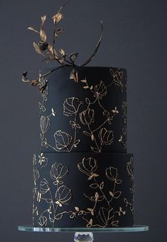 a black and gold wedding cake with flowers on it