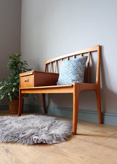 a wooden bench sitting on top of a hard wood floor next to a potted plant