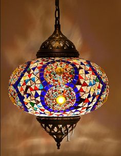 a multicolored glass light hanging from a ceiling fixture with an ornate design on it