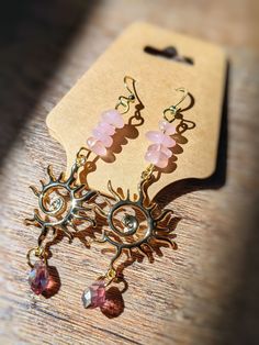 Handmade Rose Quartz gold dangle Sun Swirl earrings.☀️✨🔆 The perfect accessory for the sun goddess in your life. Lightweight for comfortable every day wear. Rose Quartz stones, brass gold plated sun pendants, & crystal tear drop beads dangling on 18k gold plated hypoallergenic fish hook earring wire. Handmade with love! 💗🌸 **I started my crystal suncatcher business in 2022 in memory of my soulmate fur-kitty, Peep, who absolutely adored the sunshine. He was the sunshine of MY life, so in his honor, I create beautiful pieces that capture the sun he loved so much. Thank you for supporting my business Bohemian Gold Rose Quartz Jewelry, Gold Spiritual Drop Crystal Earrings, Handmade Pink Spiritual Earrings, Pink Bohemian Crystal Earrings, Rose Quartz Drop Earrings Gift, Rose Gold Quartz, Rose Quartz Earrings, Swirl Earrings, Rose Quartz Stone