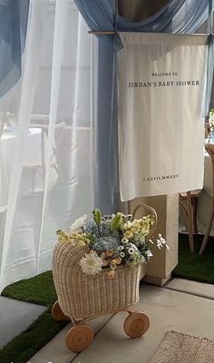 a baby stroller with flowers in it sitting on the floor next to a window