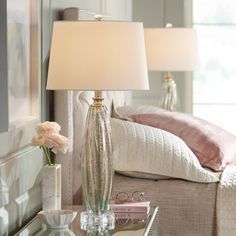 a bedroom scene with focus on the nightstand and lamp next to the bed's headboard