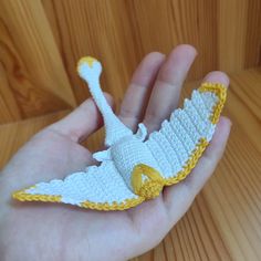 a hand holding a crocheted white and yellow bird