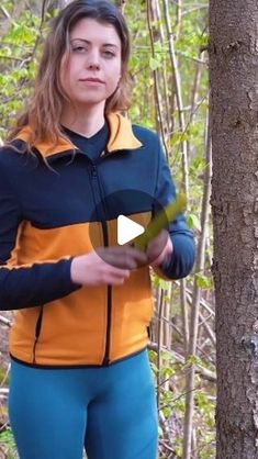 a woman standing next to a tree in the woods