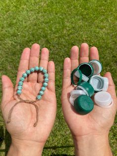 two hands holding beads and other items in the grass