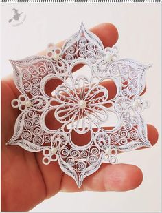 a hand holding a white paper ornament in it's left hand,