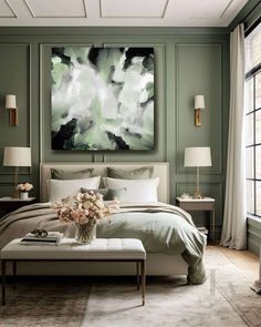 a large painting hangs above the bed in this green and white bedroom with an ottoman