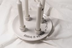 four white candles are on a plate with writing