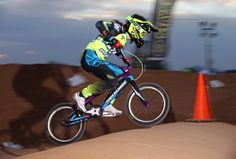 a person riding a bike on top of a dirt hill with an orange cone in the background