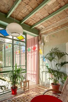 a living room filled with lots of plants next to a window covered in glass doors