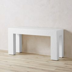 a white bench sitting on top of a hard wood floor next to a beige wall