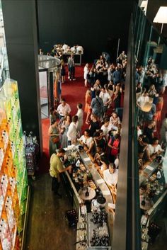 a large group of people standing around in a room full of food and drink bottles