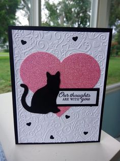 a card with a black cat on it's side and a pink heart in the middle