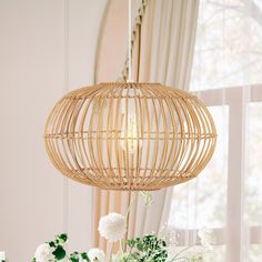 a table with flowers and vases on it in front of a window, next to a bamboo light fixture