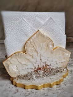 a white and gold decorative object sitting on top of a marble counter next to a tissue dispenser