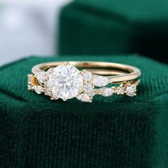 a close up of a ring on top of a green velvet cushioned surface, with two diamonds in the middle