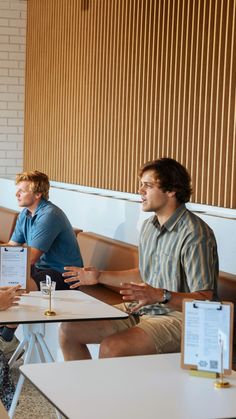 three people sitting at a table talking to each other