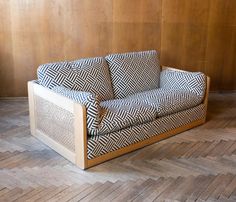 a black and white couch sitting on top of a hard wood floor next to a wooden wall