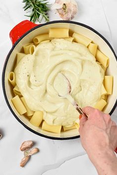 a person is spooning sauce over some pasta in a skillet